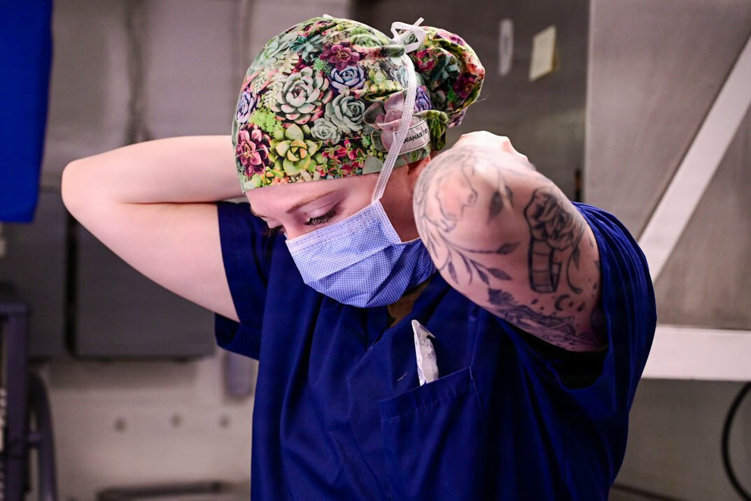 Man nurse with short hair and beard in navy scrubs portrait